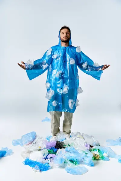 Um homem está em uma capa de chuva de plástico azul em uma pilha de resíduos plásticos. — Fotografia de Stock