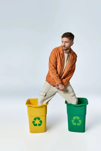 Um homem está em duas caixas de reciclagem. — Fotografia de Stock