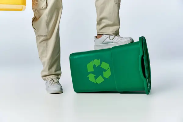 A man's foot rests atop a green recycling bin, highlighting the importance of sustainability. — Stock Photo