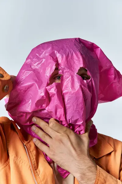 A man wears a pink plastic bag over his head, looking through two cut-out holes. — Stock Photo