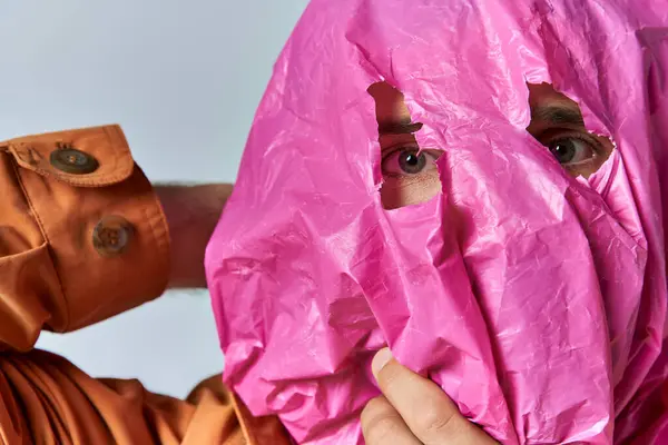 A man with a pink plastic bag over his face, peering through a hole in the material. — Stock Photo