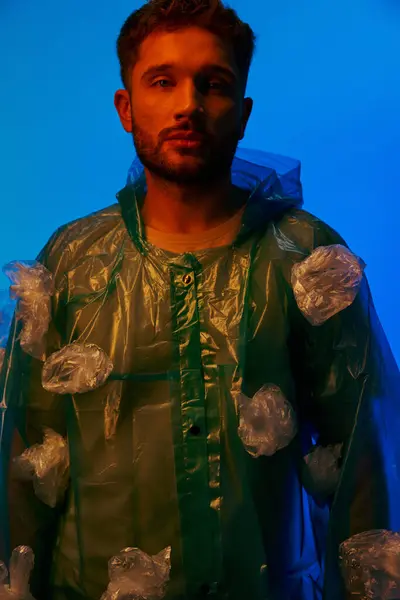 Un homme orné d'un manteau en plastique, posé sur un fond bleu vif. — Photo de stock
