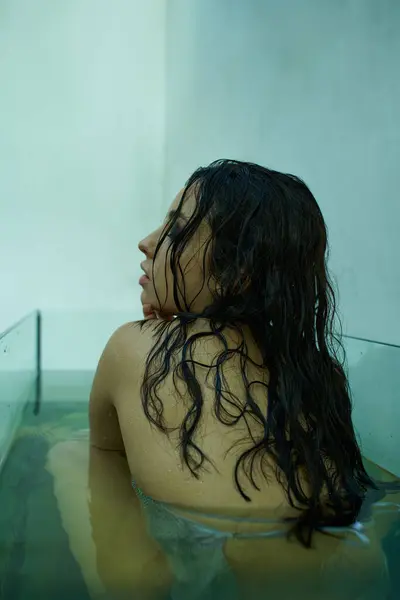 A young woman with wet hair relaxes in a clear aquarium filled with water. — Stock Photo