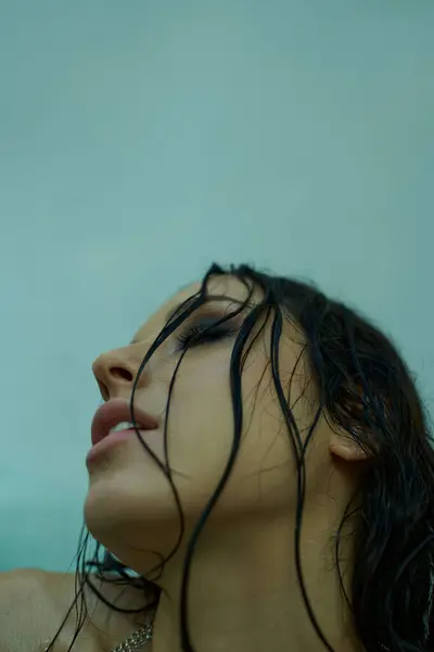 A young woman with wet hair submerged in water gazes upwards, her expression serene and thoughtful. — Stock Photo