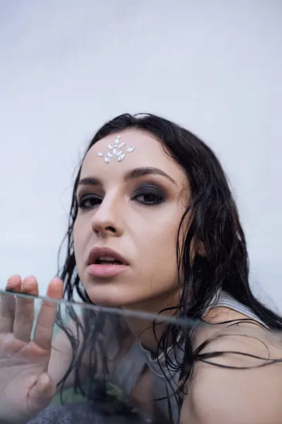 Una giovane donna dai capelli bagnati, ornata di gioielli, guarda intensamente lo spettatore da sotto la superficie dell'acqua. — Foto stock