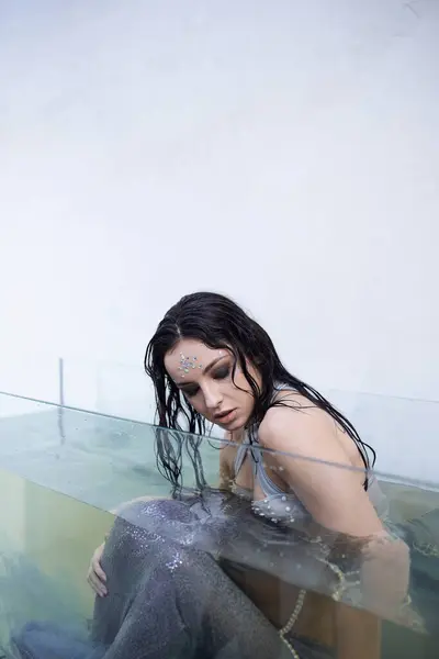 Una joven, vestida de sirena, se sienta en un acuario, con la cabeza inclinada en contemplación. — Stock Photo