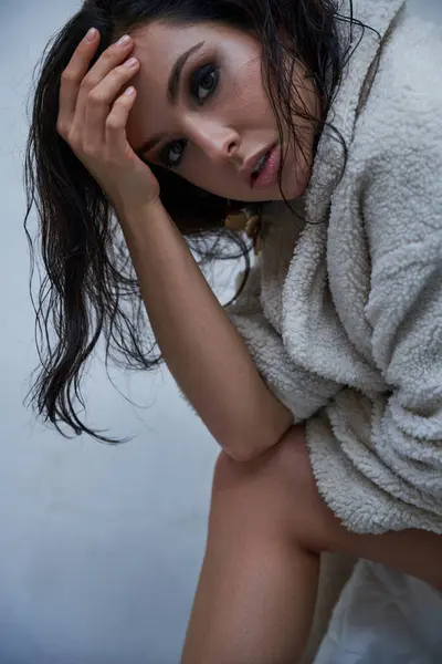 A woman with brunette hair poses in a white teddy coat in a studio setting. — Stock Photo