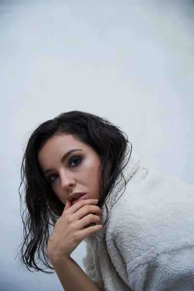 A young woman with long dark hair wears a fluffy white teddy coat while posing in a studio. — Stock Photo