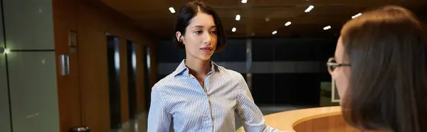 A woman with a prosthetic leg and another colleague chat in an office lobby. — Stock Photo