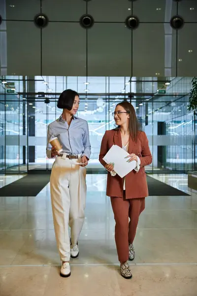 Two colleagues, one with a prosthetic leg, walk and talk in the office lobby. — Stock Photo