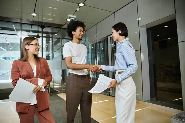 Drei Kollegen plaudern und schütteln Hände in einer modernen Büro-Lobby. — Stockfoto