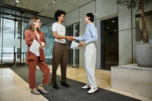 Three colleagues stand in an office lobby, engaged in a friendly conversation. — Stock Photo