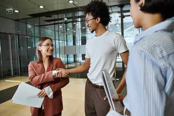 Three colleagues smile and chat in an office lobby. — Stock Photo