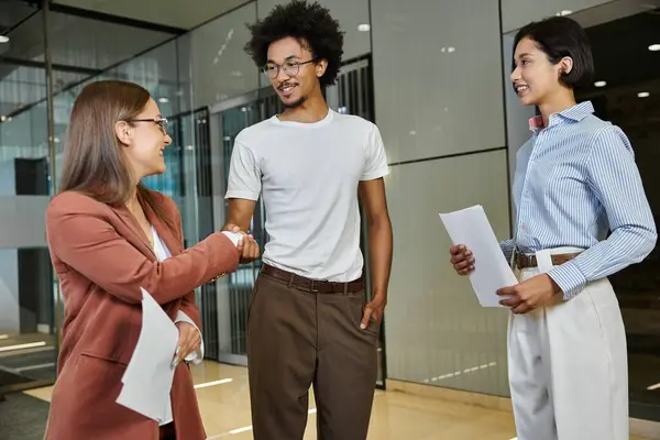 Colleagues chat in an office lobby, demonstrating diversity in the workplace. — Stock Photo