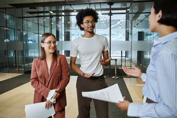 Three colleagues stand and converse in an office lobby. — Stock Photo
