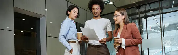 Tre colleghi chattano e rivedono i documenti nella hall dell'ufficio. — Foto stock