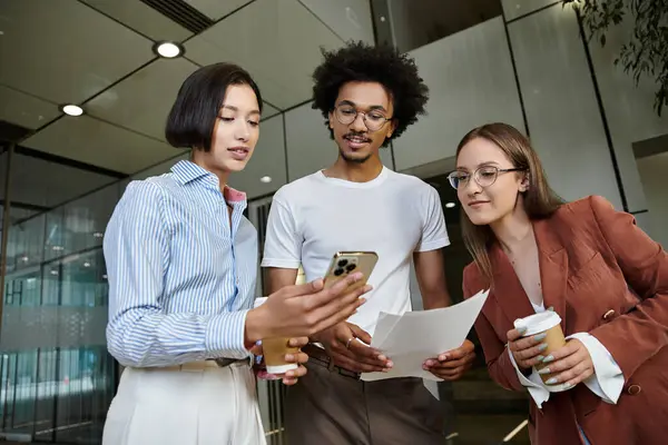 Three colleagues, chat and look at a smartphone in an office lobby. — Stock Photo