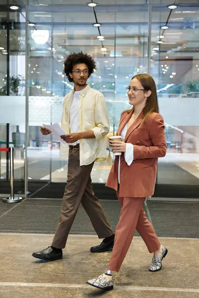 Deux collègues, l'un avec une jambe prothétique, bavardent et marchent dans un hall d'entrée de bureau. — Photo de stock