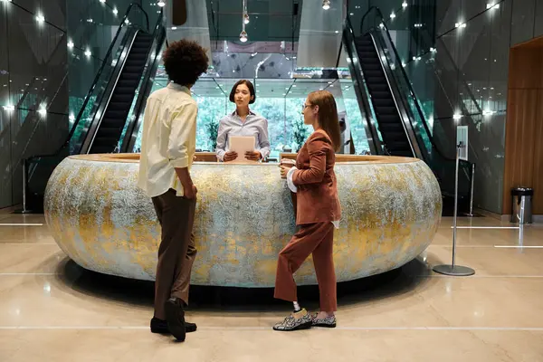 A diverse group of colleagues chat in the office lobby, sharing a friendly conversation while standing by a unique counter. — Stock Photo