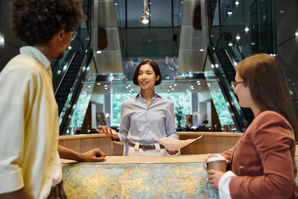 Three colleagues, chat and laugh while standing in an office lobby. — Stock Photo