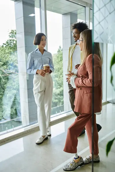 Three colleagues chat and laugh together in a modern office space, one woman wearing a prosthetic leg. — Stock Photo