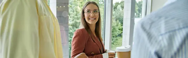 A smiling woman chats with colleagues in a modern office setting — Stock Photo