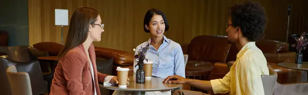 Three colleagues enjoy a friendly conversation over coffee in a modern office setting. — Stock Photo