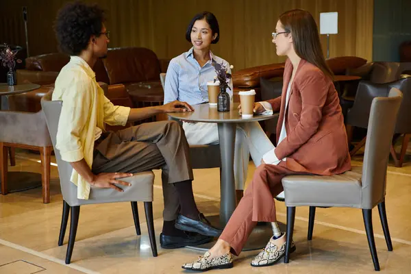 Diverse colleagues enjoy a coffee break in a modern office, chatting and laughing. — Stock Photo