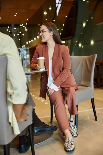 Inclusive and respectful culture shown in modern office as woman in suit chats with colleague. — Stock Photo