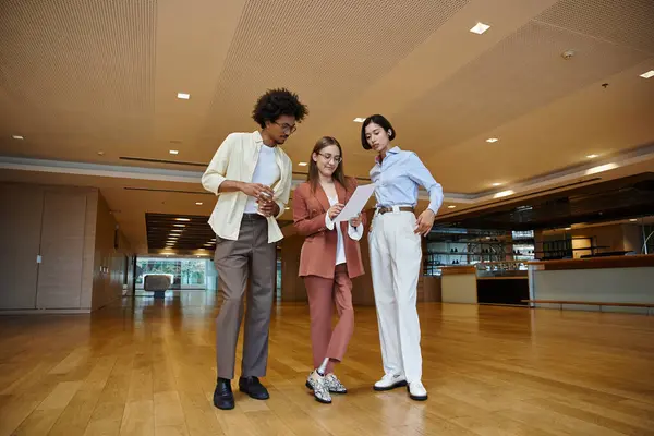 Three colleagues, including a woman with a prosthetic leg, are discussing a document in a bright office space. — Stock Photo