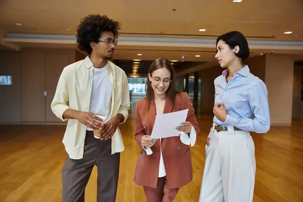 Three colleagues, stand in a modern office and chat amicably. — Stock Photo