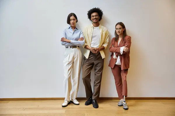 Three colleagues stand in a modern office, smiling and looking confident. — Stock Photo