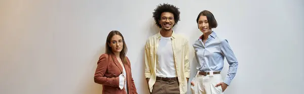 Three diverse colleagues chat casually in a modern office setting. — Stock Photo