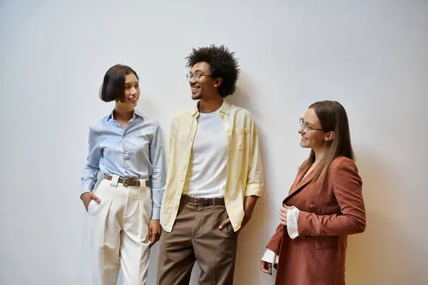 Three colleagues stand in an office, engaging in a friendly conversation. — Stock Photo