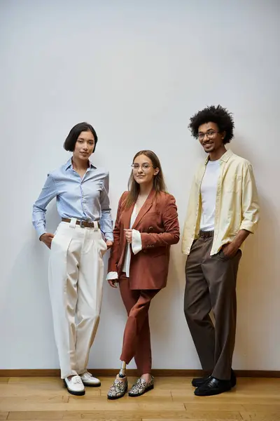 Trois collègues se tiennent ensemble dans un bureau moderne, bavardant et riant. — Photo de stock