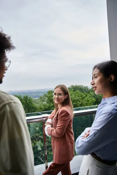 Diverse group of colleagues enjoy a conversation on a rooftop terrace overlooking the city. — Stock Photo
