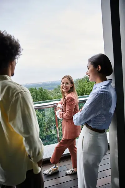 Three colleagues chat on a modern office rooftop terrace, enjoying the view. — Stock Photo