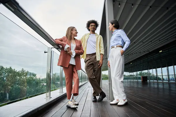 Diverse colleagues enjoy a friendly conversation on a modern office rooftop terrace. — Stock Photo