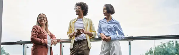 Three colleagues, stand on a rooftop terrace and chat. — Stock Photo