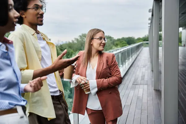 Three colleagues chat on a modern office rooftop terrace. — Stock Photo