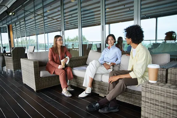 Three colleagues, including a woman with a prosthetic leg, enjoy a relaxed conversation on a rooftop terrace, enjoying coffee and the view. — Stock Photo