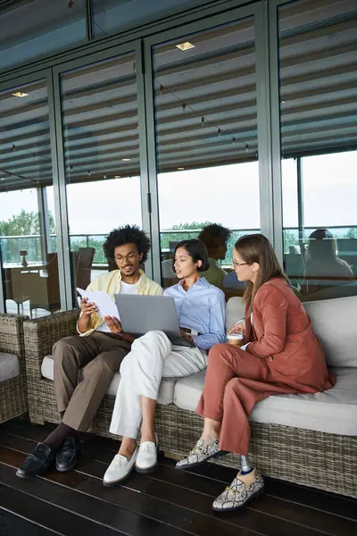 Diverse colleagues relax on a rooftop terrace, enjoying a casual work conversation. — Stock Photo