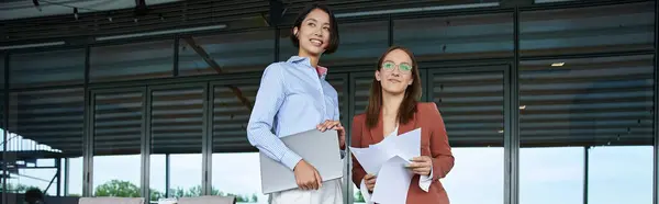 Two colleagues stand on a modern rooftop terrace, engaging in a friendly conversation. — Stock Photo