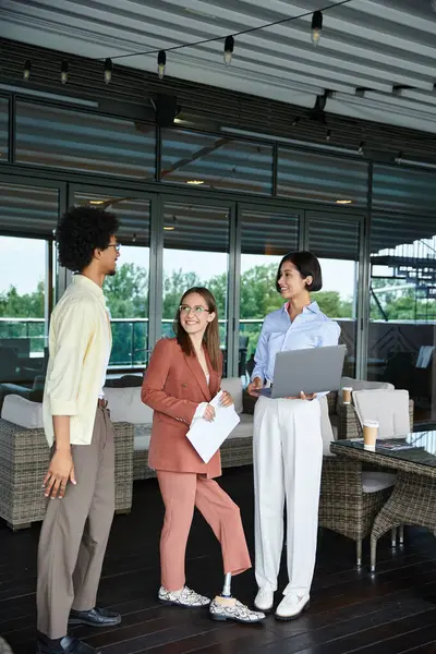 Diverse colleagues chat amicably on a rooftop terrace, enjoying a break from the office. — Stock Photo