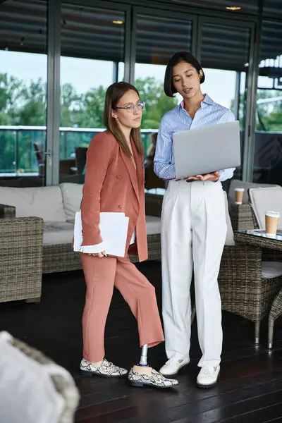 Two colleagues, one with a prosthetic leg, chat on a rooftop terrace, embodying diversity and inclusion in the workplace. — Stock Photo
