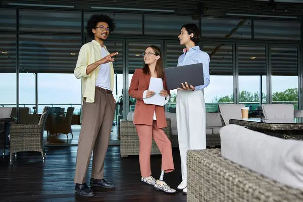 Drei Kollegen, darunter eine Frau mit Beinprothese, plaudern und lachen auf einer modernen Dachterrasse. — Stock Photo