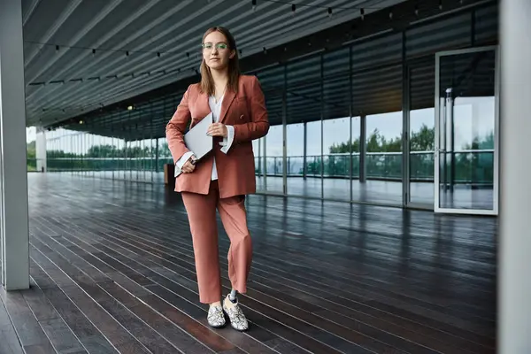 Una mujer con una pierna protésica se levanta en una moderna terraza de oficina con un portátil en la mano. — Stock Photo