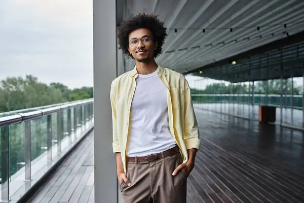 A man with glasses smiles brightly while standing on a modern office rooftop terrace. — Stock Photo