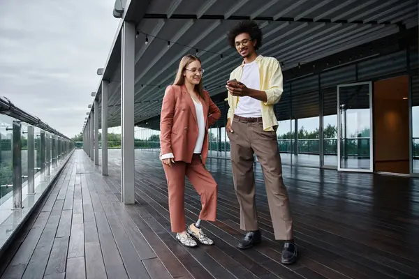 Two colleagues, a woman with a prosthetic leg and a man, stand on a rooftop terrace, engaged in a friendly conversation. — Stock Photo