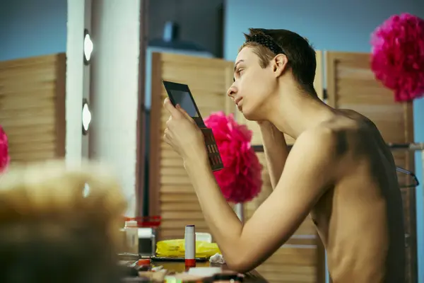 A drag queen applies makeup in front of a mirror, getting ready for a performance. — Stock Photo